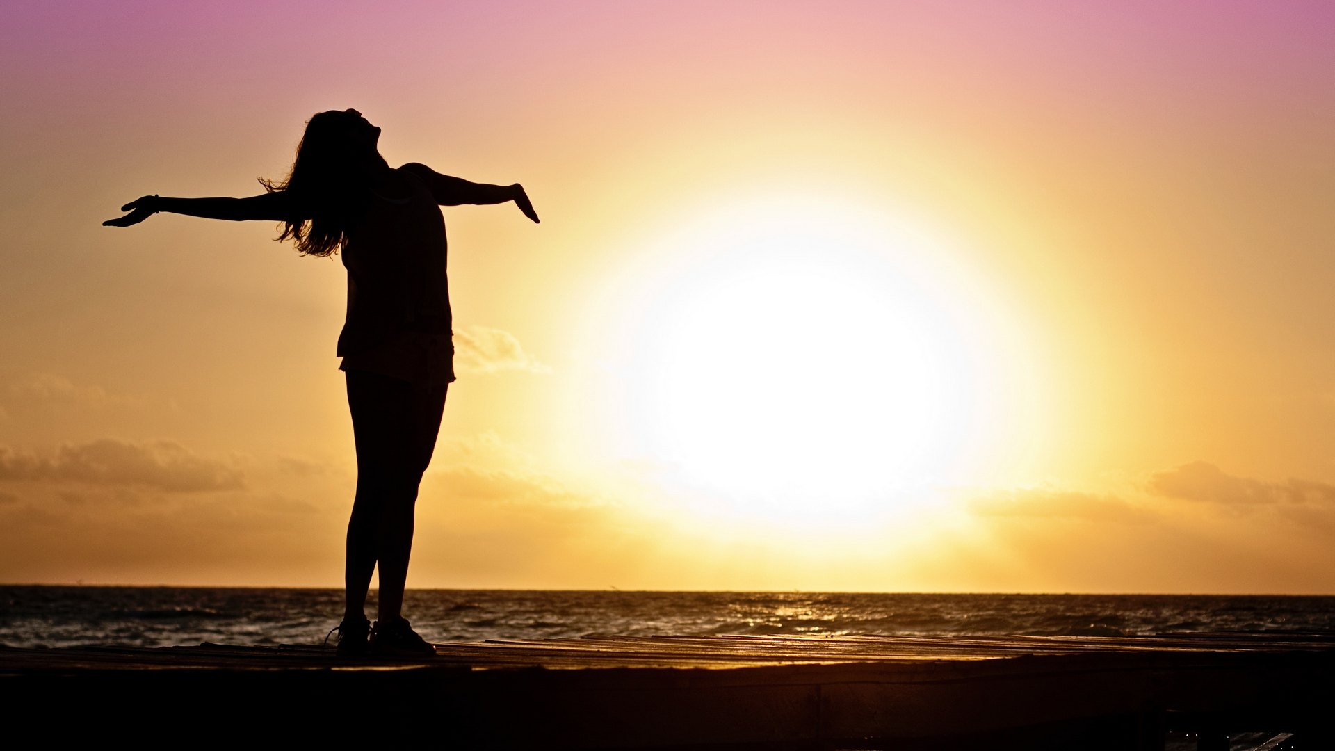 Silhouette of a women at the ocean in front of the sunset