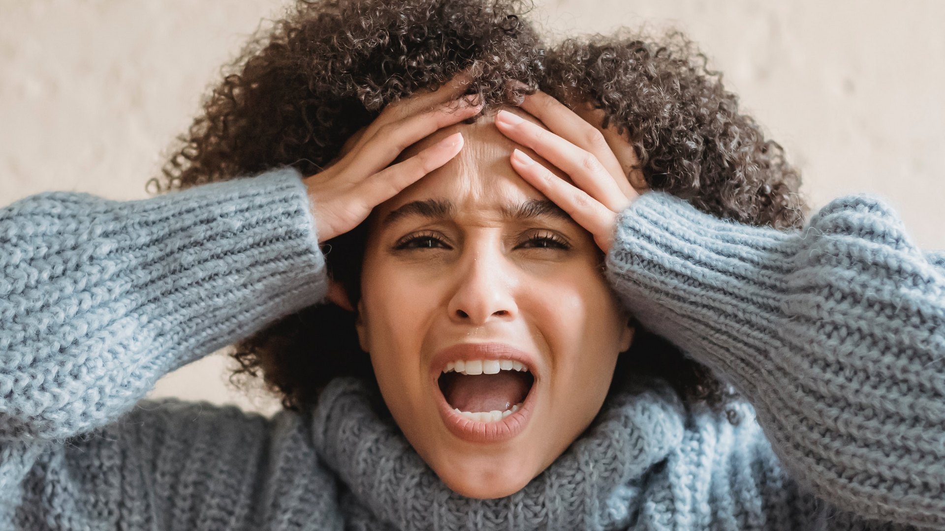 Photo of a women screaming and holding her head